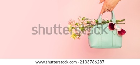 Fashion spring accessories for woman - banner. Small mint green handbag (purse), heart shaped sunglasses and flowers on pastel pink background. Free copy (text) space.