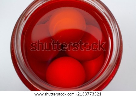 Chicken eggs in red in a glass jar with red liquid. Photo for Happy Easter.