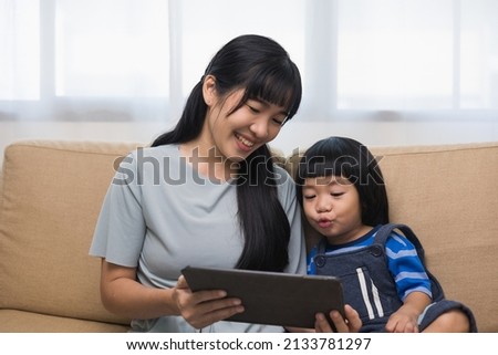 Happy asian family mother and  son using tablet for education. Little boy watching funny social media.  Mom with kid using tablet video call to father. Royalty-Free Stock Photo #2133781297