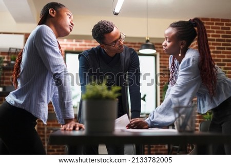 African american business company colleagues in meeting about startup project financial status. Marketing agency team members reviewing accounting documentation and revenue statistics data.