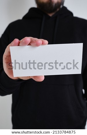 White empty card in the hands of a man on a black background. Place for text and advertising. Business card