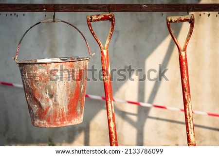 Chemical spill recovered equipment such as metal bucket and shovel are hanging with hook on the metal rail for housekeeping and storage. Emergency or working tool object photo.