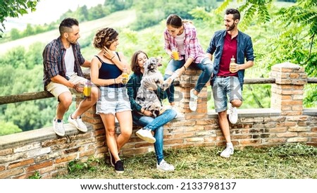 Young friends playing with dog at pic nic by countryside farm house - Healthy alternative life style concept with happy millenial people having fun together out side at garden party - Bright filter Royalty-Free Stock Photo #2133798137