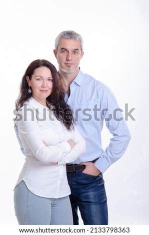 Youthful white European 40s couple in studio photography. Happy heterogeneous man and woman in jeans and shirts wearing white and blue clothes.