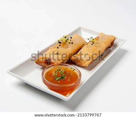 Front view of two spring rolls stuffed with vegetables on long tray on white background accompanied by bittersweet in round container Royalty-Free Stock Photo #2133799767