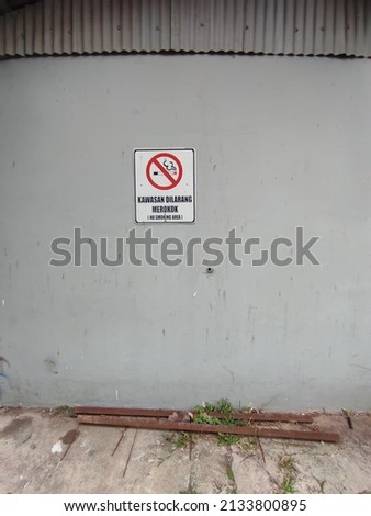no smoking sign in the middle of a dirty white wall