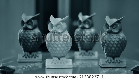 Four 3d models of owls created on a 3d printer stand on the desktop of 3d printer close-up. Progressive modern additive technologies 4.0 industrial revolution