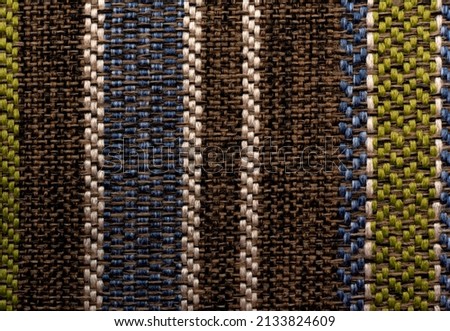 The texture of a dense upholstery fabric with straight multi-colored lines and stripes. Fabric background. pattern