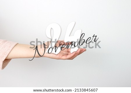 November 24th. Day 24 of month, Calendar date. Calendar Date floating over female hand on grey background. Autumn month, day of the year concept