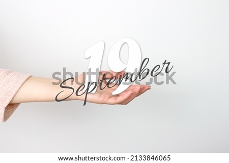 September 19th. Day 19 of month, Calendar date. Calendar Date floating over female hand on grey background. Autumn month, day of the year concept