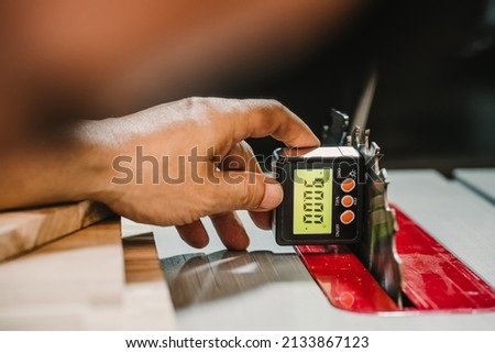 carpenter use Horizontal Angle Meter or Digital Inclinometer to align blades and fences on tablesaw at workshop,woodworking concept.selective focus.
