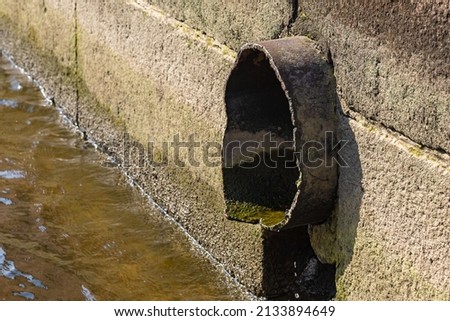 part of the pipe coming out of the granite embankment to the river. background picture.