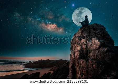 person silhouette sitting on the top of the mountain meditating or contemplating the starry night with Milky Way and Moon background	 Royalty-Free Stock Photo #2133899101