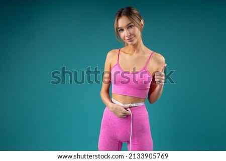 slim young woman measures her figure with tape with hand gesture	