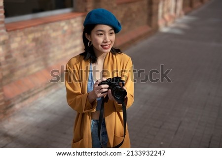 Beautiful Chinese woman with camera. Happy smiling woman taking photos of beautiful location	
