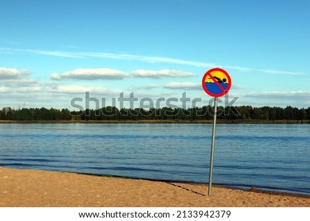 Sign prohibiting swimming on the beach by the shore of a lake or river Royalty-Free Stock Photo #2133942379