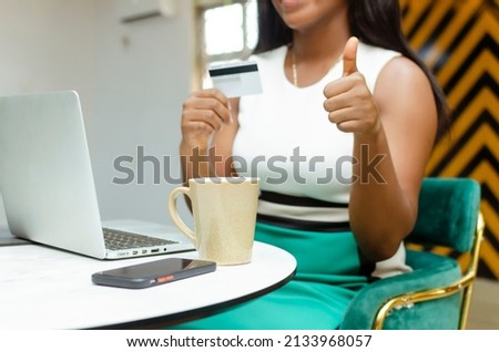 cropped picture of young female holding credit card with fingers and holding up thumbs.