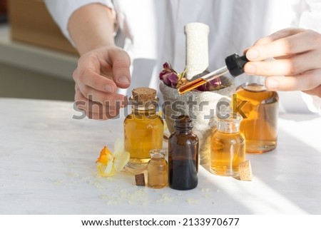 Female scientist doing laboratory research with natural organic essential oils and flower extracts. White background. High quality photo