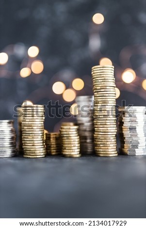 stacks of different golden and silver coins creating a big amount of savings shot on dark background with fairy light, concept of abundance and reaching your savings goals