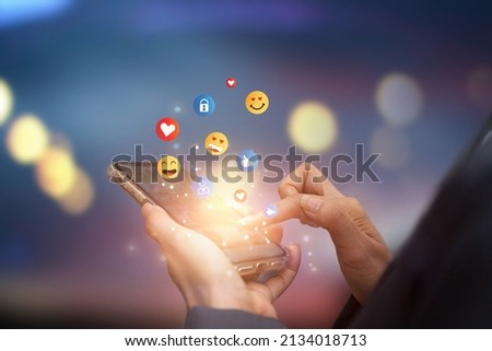 Young man using smartphone sending emojis. Mobile smartphone sending text messages emoji emoticon. Royalty-Free Stock Photo #2134018713