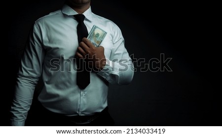 Businessman standing holding dollar on black background with space for text input. corruption,bribe.