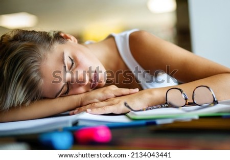 Portrait of tired young female studying in a library. Education study teenager concept