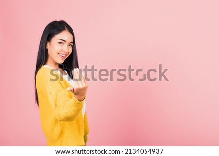 Happy Asian portrait beautiful cute young woman teen smile positive friendly making gesture hand inviting to come here with hand look to camera studio shot isolated on pink background with copy space Royalty-Free Stock Photo #2134054937