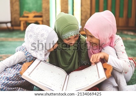 Group of a children reading a holy book Quran in the mosque. Happy Muslim family. Muslim girls in hijab studying Islam religion.  Royalty-Free Stock Photo #2134069425