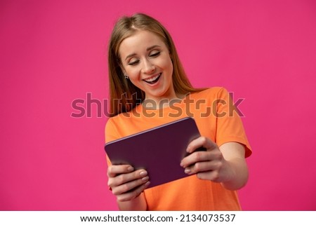 Young woman using digital tablet against pink background