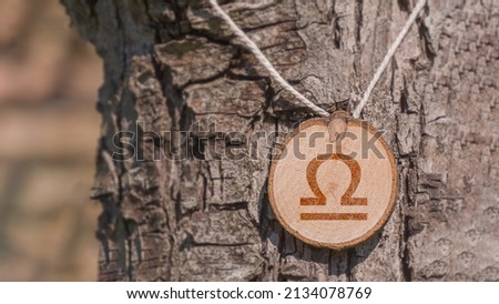 Close-up shot of a piece of wood with a zodiac sign engraved on it, especially the libra sign