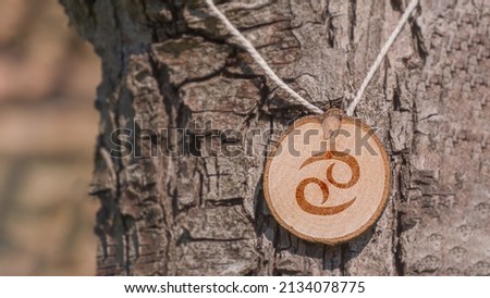 Close-up shot of a piece of wood with a zodiac sign engraved on it, especially the cancer sign