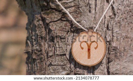 Close-up shot of a piece of wood with a zodiac sign engraved on it, especially the aries sign