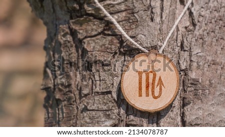 Close-up shot of a piece of wood with a zodiac sign engraved on it, especially the scorpio sign