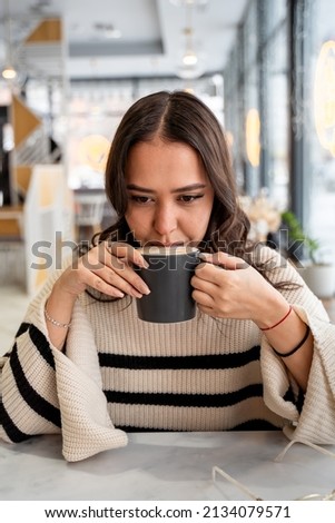 Young woman drinking coffee from a mug in a cafe, freelancer,lunch break. High quality photo