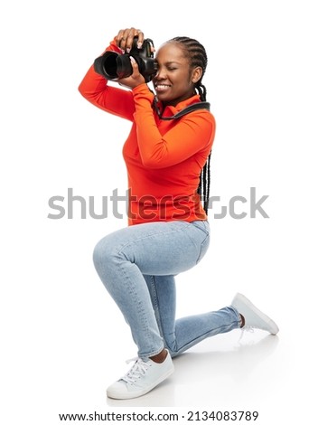 people, profession and photography concept - happy smiling woman photographer with digital camera photographing over white background