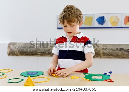 Happy kid boy having fun with building and creating geometric figures, learning mathematics and geometry