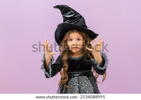 A surprised witch in a magical costume on an isolated background. A joyful sorceress in a magician's hat.