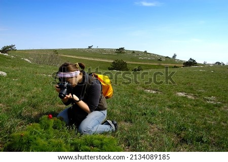 Woman taking photographs of red flowers in a spring garden
