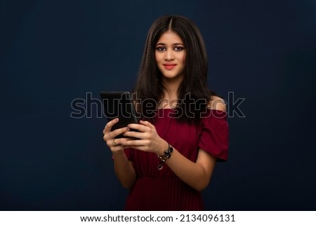 Young beautiful girl holding and using smartphone or mobile or tablet phone on a grey background.