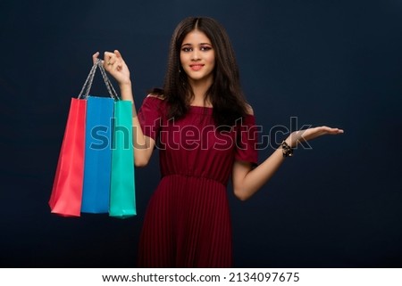 Beautiful Indian young girl holding and posing with shopping bags on a dark background