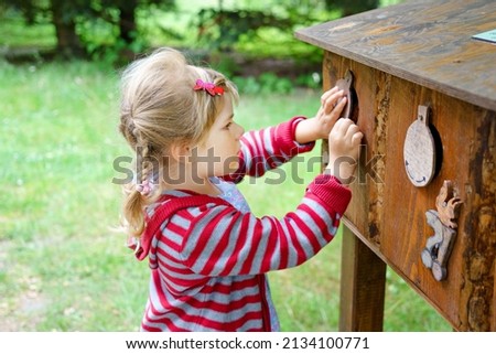 Little preschool girl exploring life of squirrels in forest. Active happy child learning about food of animals. Children and environment, forest life and wild nature.