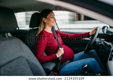 Happy pregnant woman driving car with safety belt on. Royalty-Free Stock Photo #2134105109