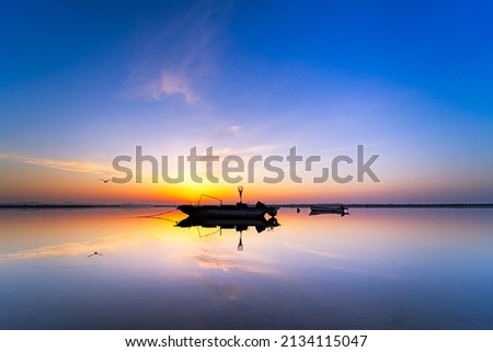 Fishing boats and the early morning sky reflected on the lake.