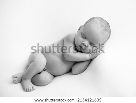 Sleeping newborn boy on a white background. Photoshoot for the newborn. Two weeks from birth. A portrait of a beautiful, newborn baby  sleeping. Newborn boy on a black and white background Royalty-Free Stock Photo #2134121605