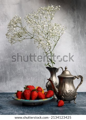 Still life photo with flowers and strawberries. Beautiful picture of fruit and flowers on a table. 