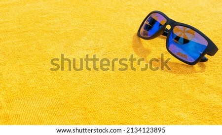 Black sunglasses summer background. Beach pool equipment with travel sunglasses on yellow holiday towel. Sun glasses near swimming pool, holiday concept