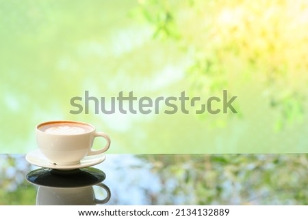 Close-up. Vintage tones Latte art coffee cup on glass table. Blurred leaf reflection background.