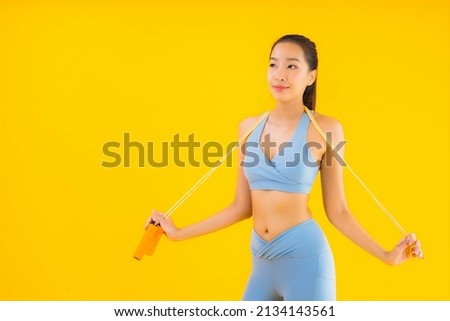 Portrait beautiful young asian woman wear sportwear with rope ready for exercise on yellow isolated background