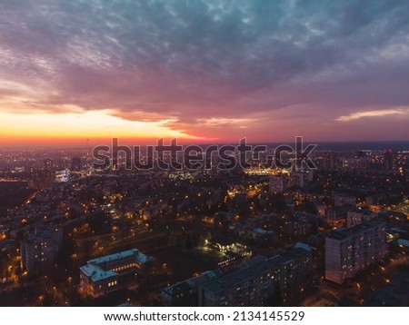 Aerial sunset orange vibrant view on Kharkiv city, Pavlove pole. Night lights on streets of residential district and scenic cloudy skyscape. Moody illuminated cityscape rooftop