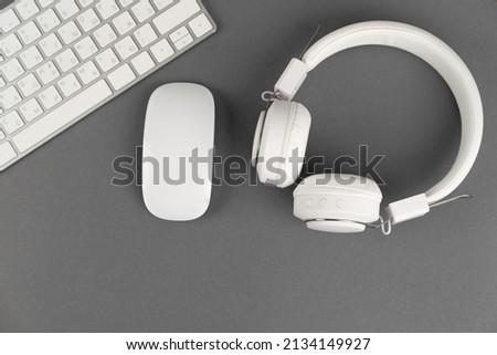 Background music or podcast with headphones and a computer keyboard on a gray table, flat. Top view, flat layout. 